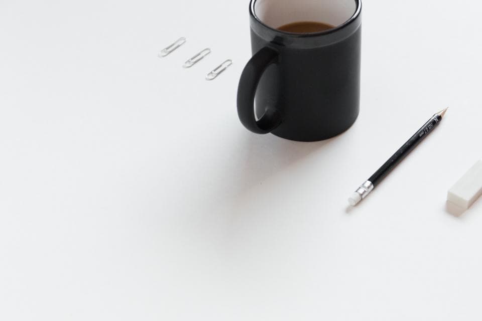 Bureau minimaliste avec tasse de café, crayon et gomme, symbole de la préparation méthodique d'une certification ISO 27001
