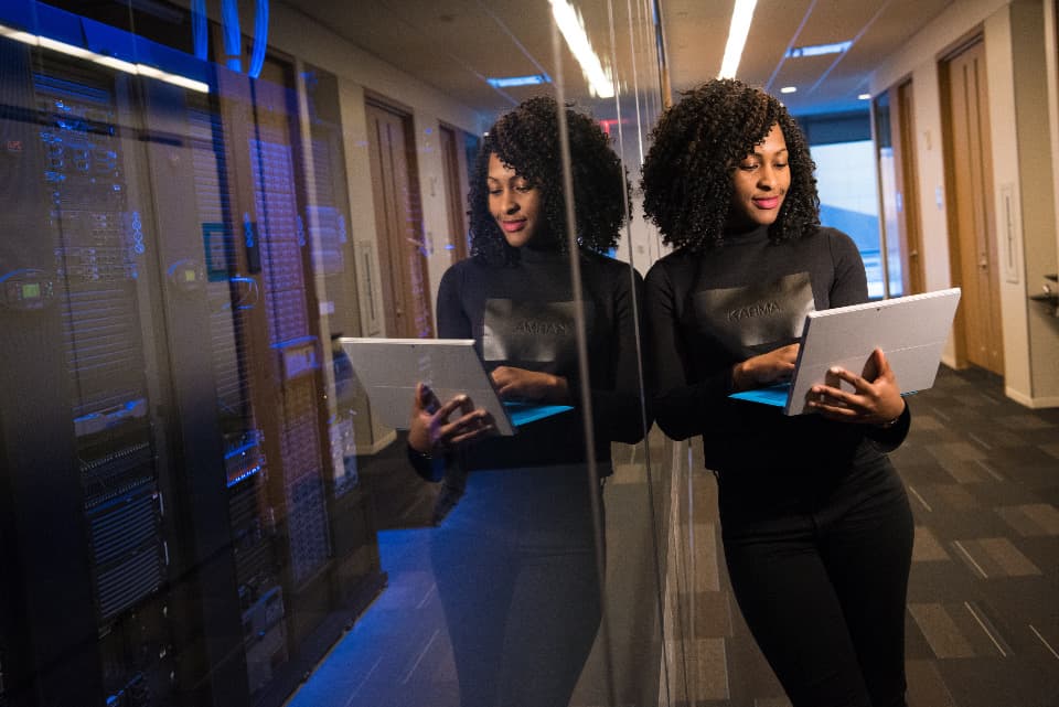 Technician checking a tablet in front of a server rack, illustrating the assessment of DevOps maturity