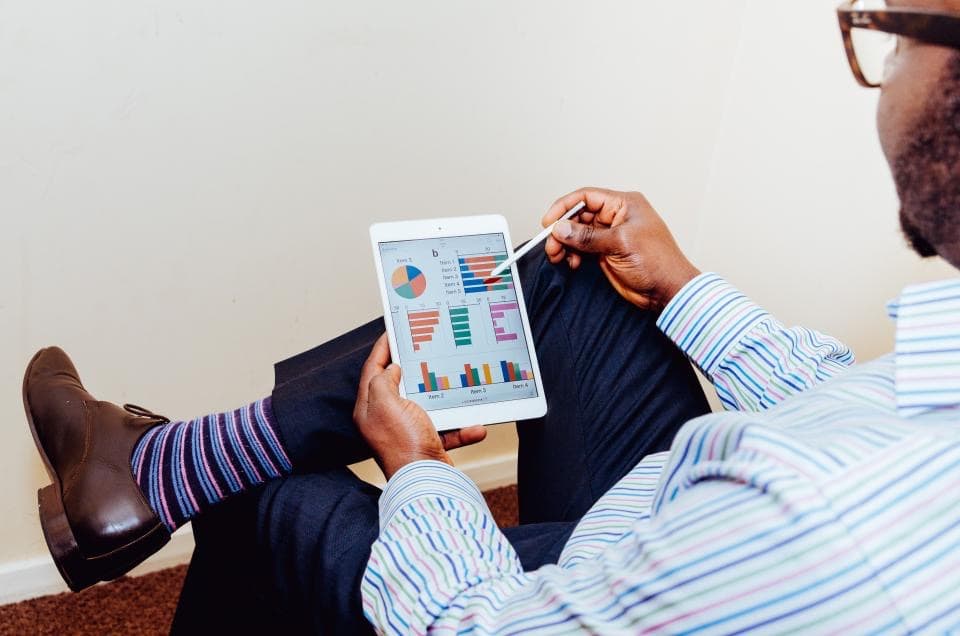 Homme d'affaires consultant des graphiques sur une tablette, illustrant la mise en place d'une gouvernance IT