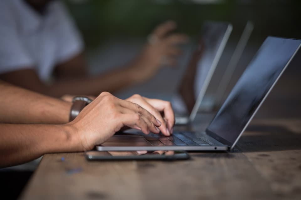 Close-up of hands typing on a laptop keyboard, illustrating good computer hygiene practices